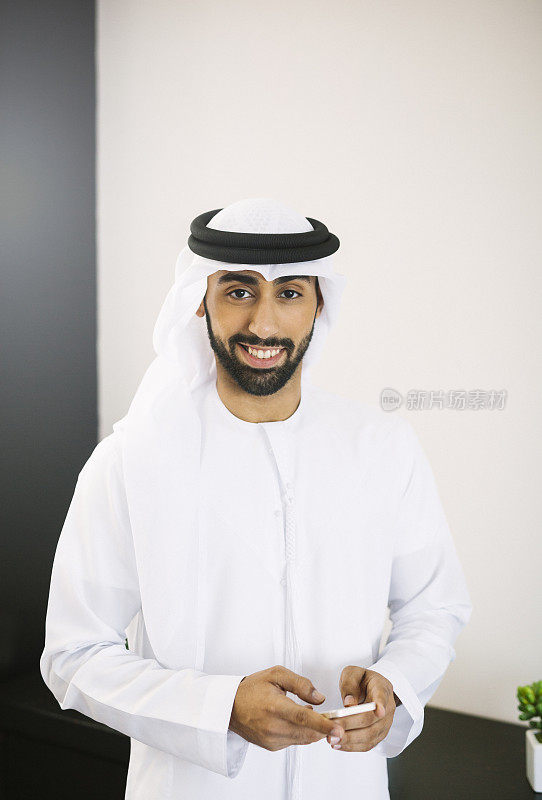 年轻成功的阿拉伯男子与智能手机的肖像
