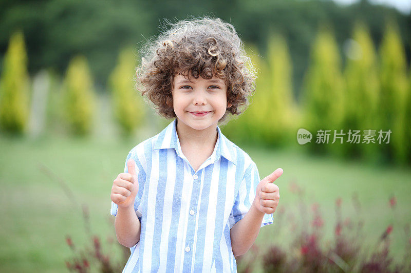 微笑的小男孩对着树竖起大拇指