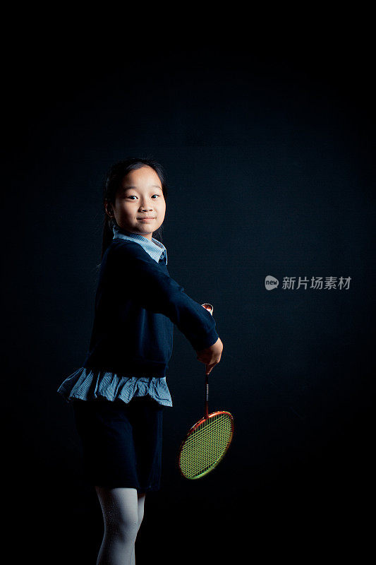小女孩打羽毛球-孤立在黑色背景