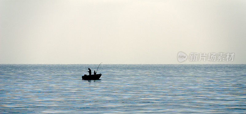 海上两名渔民在船上的剪影