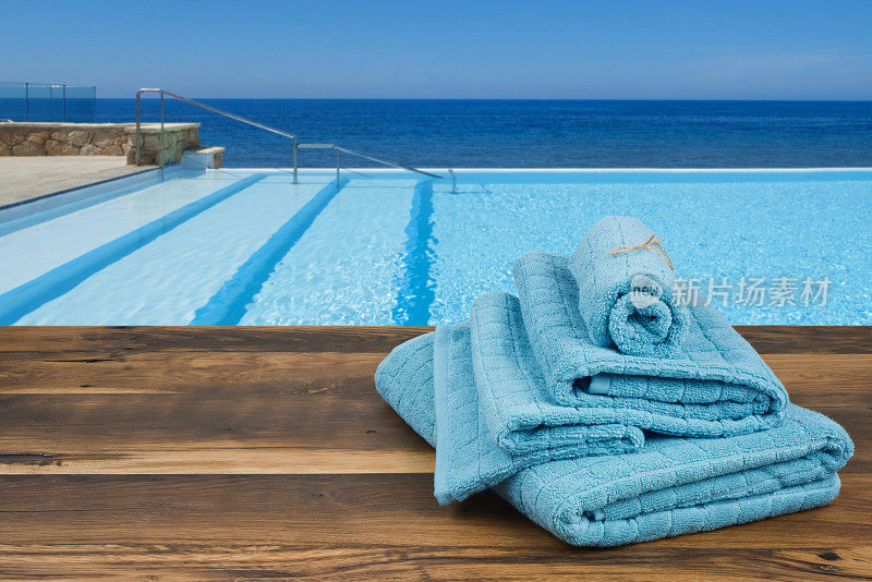 木制毛巾盖上模糊的游泳池和大海背景