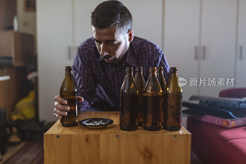 年轻悲伤的醉酒男子喝啤酒和酒精感到浪费，孤独和绝望的痛苦和情绪压力。人与酗酒、上瘾和男人抑郁的概念。