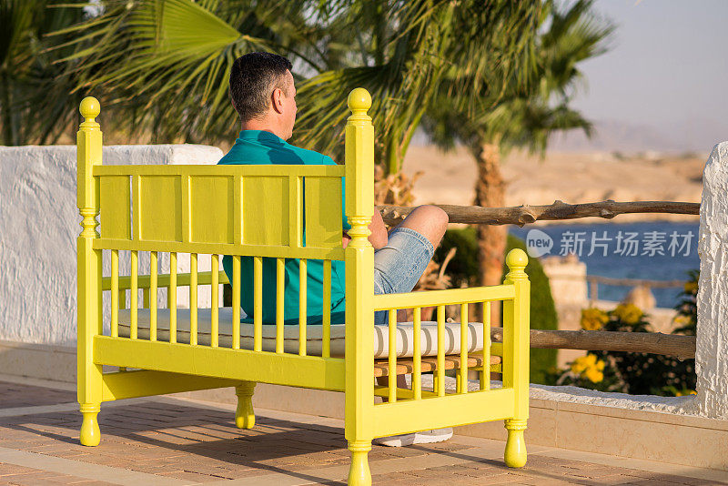 一名男子坐在彩色长凳上望着远方