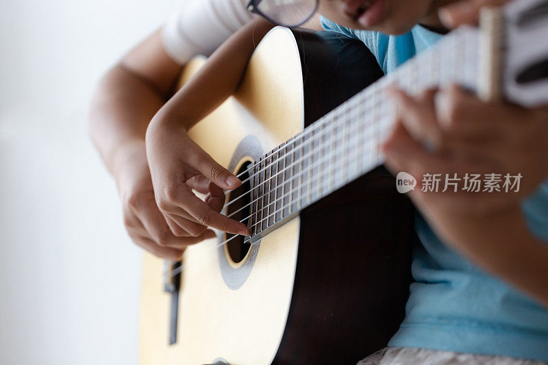 母亲教女儿学习如何弹奏古典古典吉他，为爵士乐和易听歌曲选择焦点浅景深