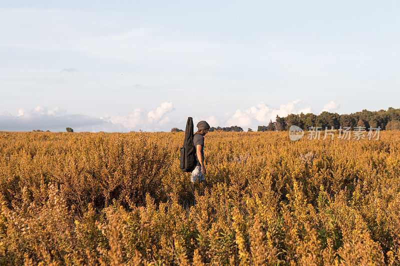 一个带着吉他的人在田野里