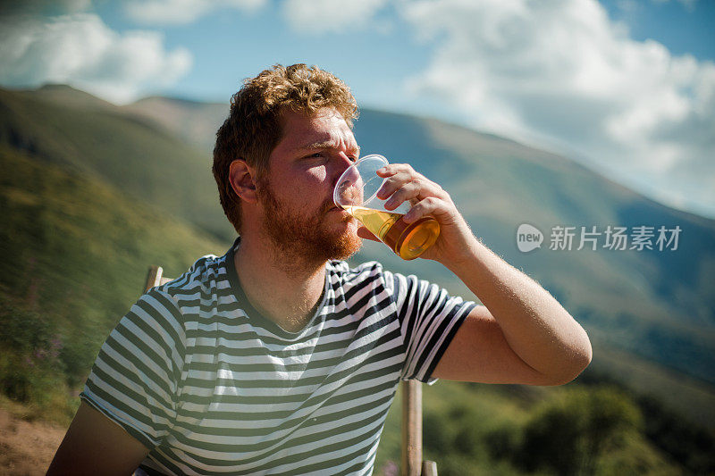 他正在山顶上喝着啤酒休息