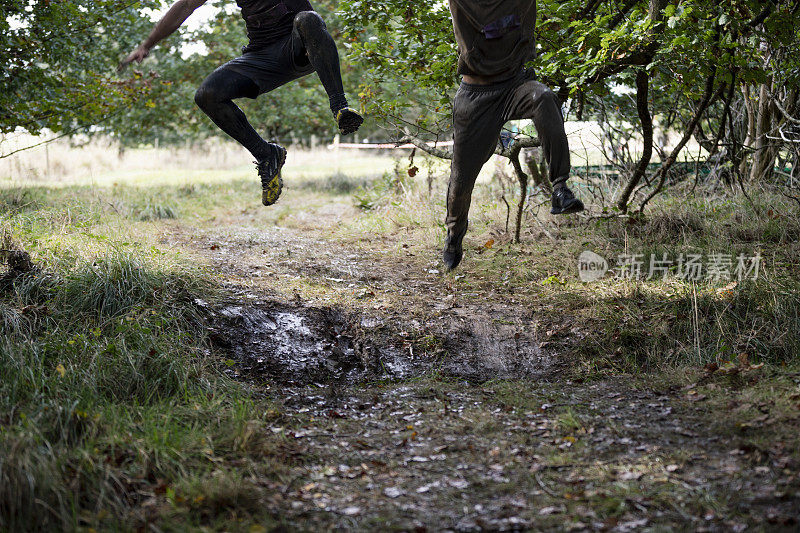 两名男子的双腿在乡间跑道上跳跃