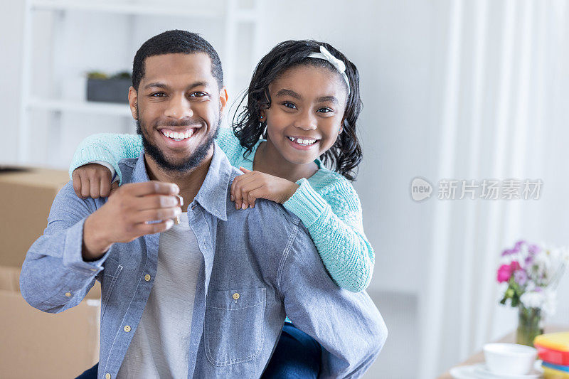 一位年轻的非洲裔美国父亲和他的小女儿一起在照相机前摆姿势