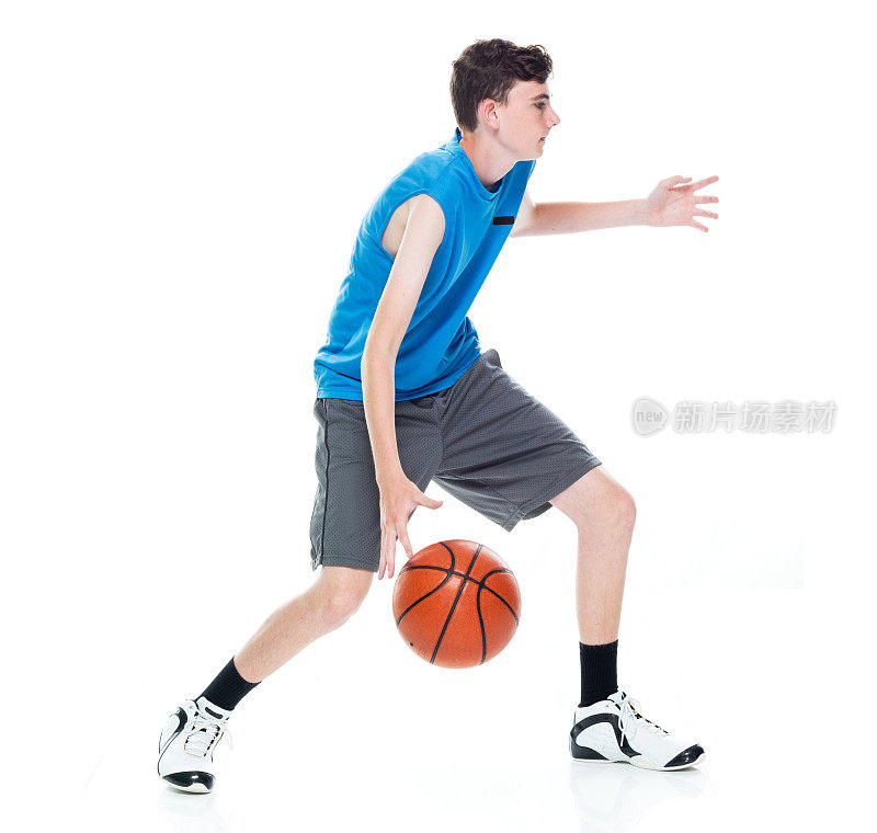 白人男孩篮球运动员在白色背景前，拿着篮球和使用运动球