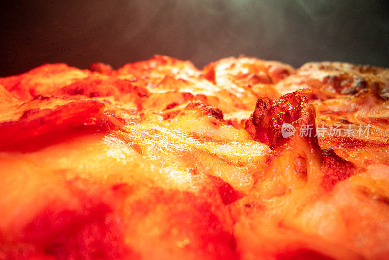 超近距离广角微距拍摄辣香肠在美味热气腾腾的深盘饼皮披萨新鲜出炉的烤箱在冷却架下加热灯与复制空间