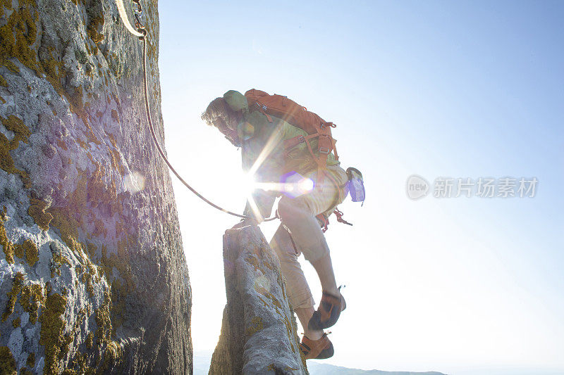 登山者在日出时攀登岩面