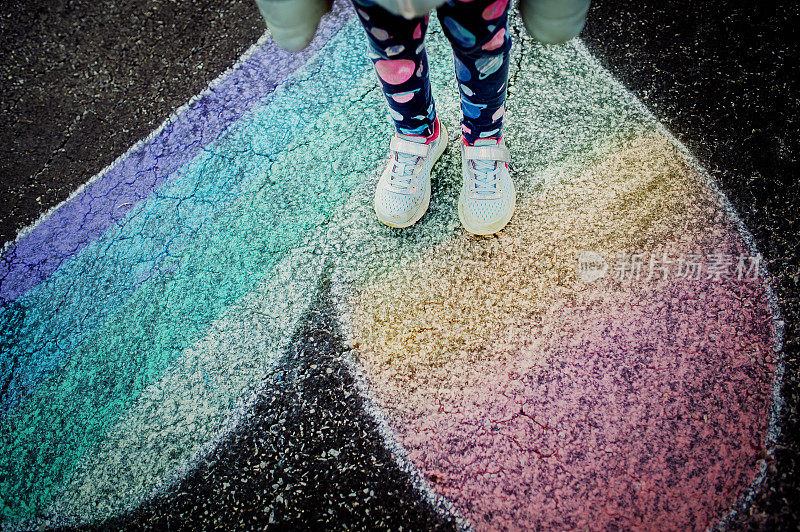 儿童站在彩虹心粉笔画