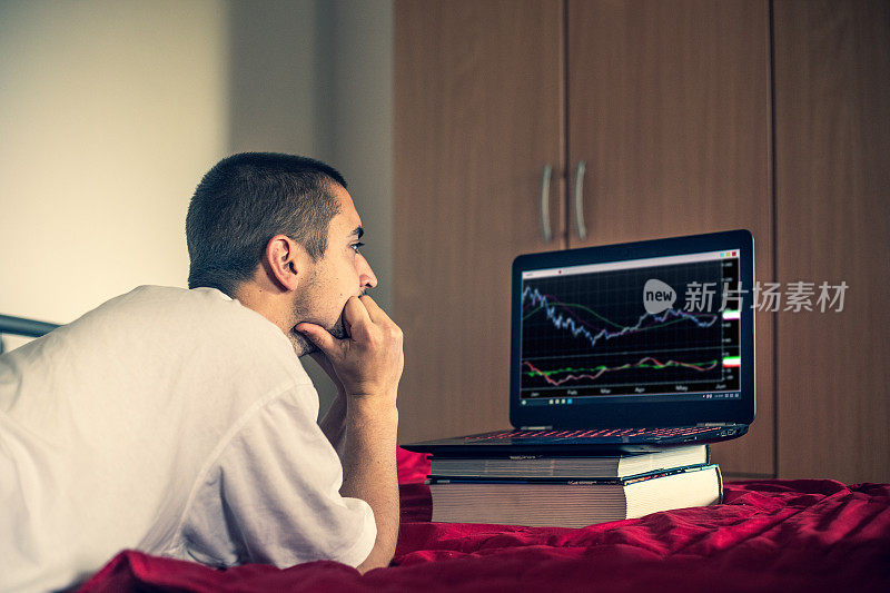年轻的成年人在笔记本电脑上看下跌的股票交易图表