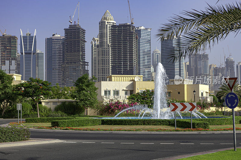 迪拜，阿拉伯联合酋长国-俯瞰喷泉和路边景观，在草地地区，朱美拉湖塔;许多将成为摩天大楼的塔楼仍在建设中