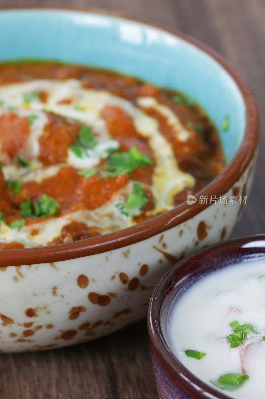 这是一碗自制的咖喱鸡，配上印度烤饼和raita(酸奶酱)的特写画面