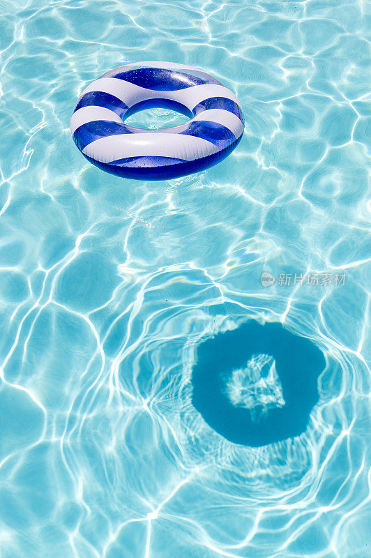条纹浮环表面上的水晶清澈的蓝色水与反射阳光和阴影