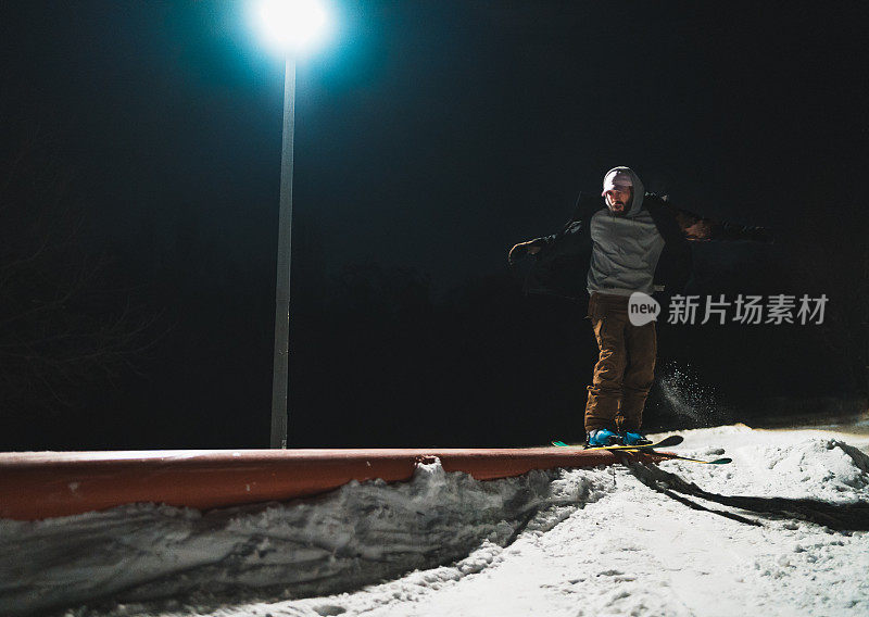 自由式滑雪运动员在夜间的特技栏杆上