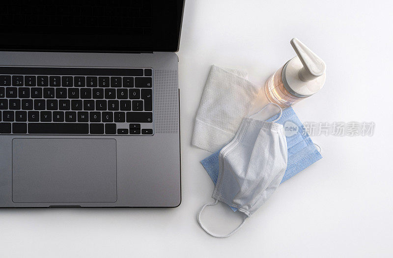 医用口罩和酒精洗手液凝胶白色背景与笔记本电脑