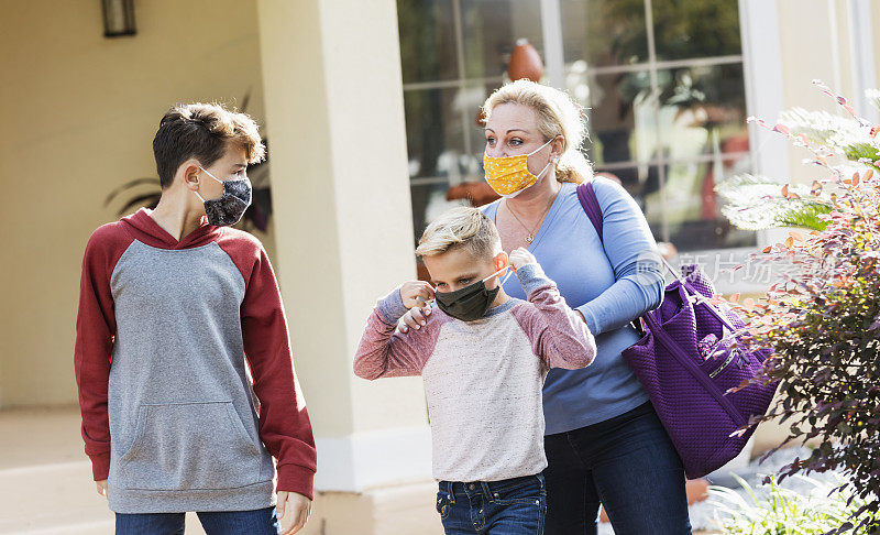 母亲和男孩们离开家时戴上了口罩