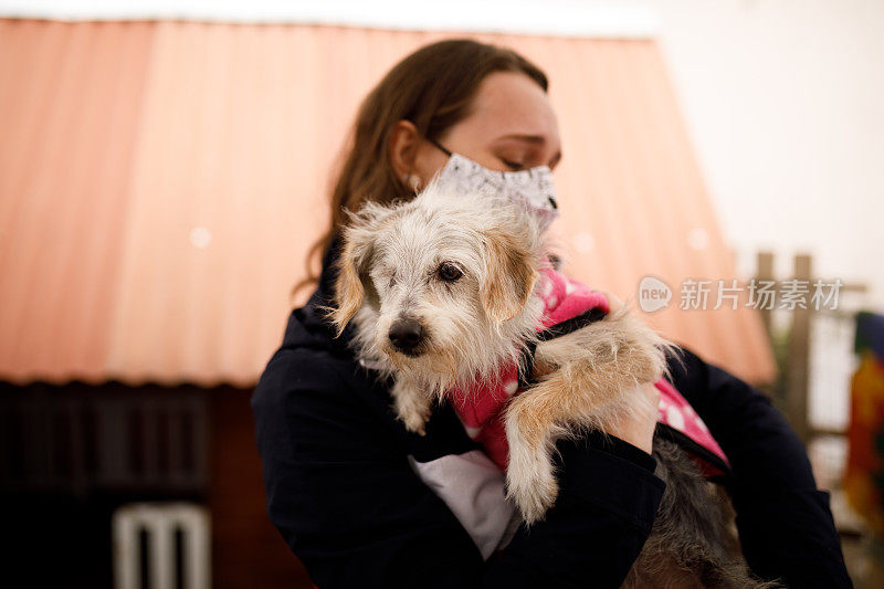 在宠物收养活动上，一个女人拥抱一只狗