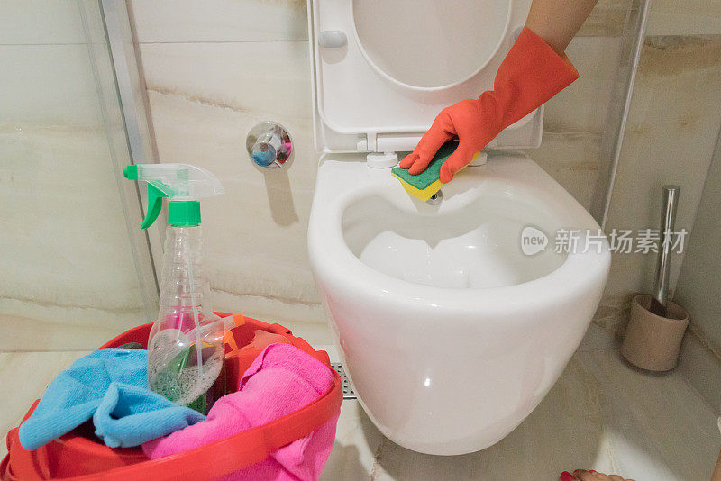 女保洁员戴着红手套用清洁海绵清洁马桶。