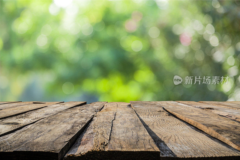 背景:空的乡村木桌与散焦绿色茂盛的树叶在背景