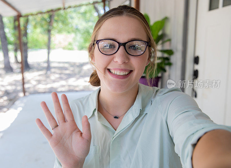 在与同事进行视频会议时，一名女子向摄像机挥手并微笑