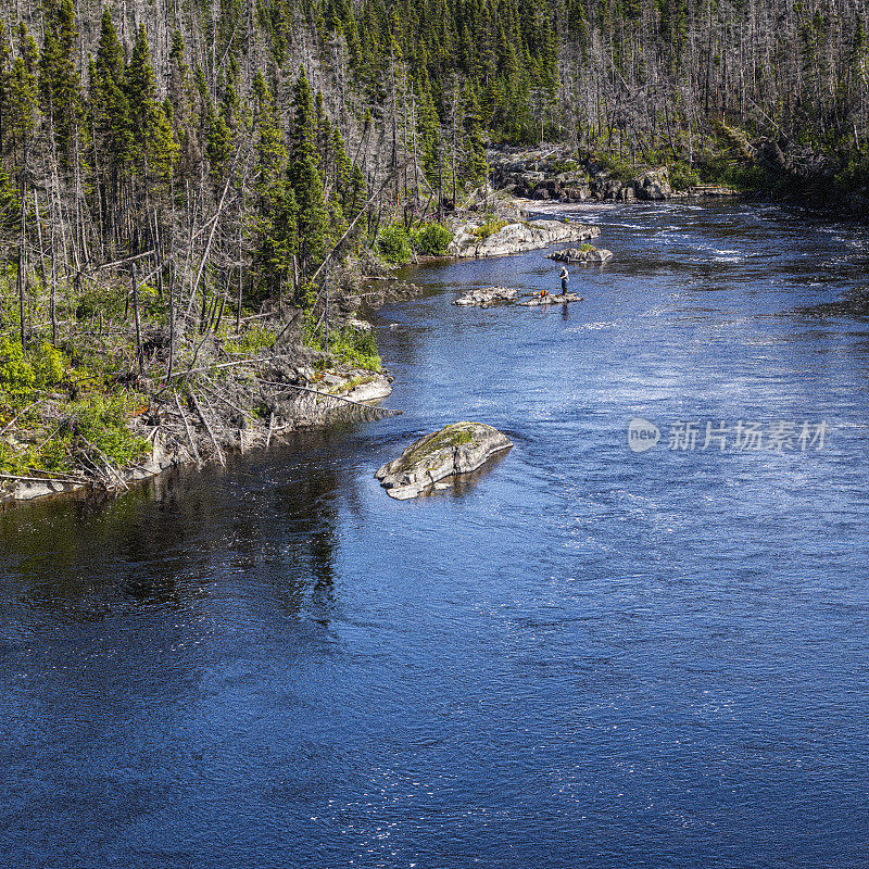 在魁北克省的北海岸，一个不知名的渔民站在奎塔丘河的岩石上，准备捕捉一些鱼。