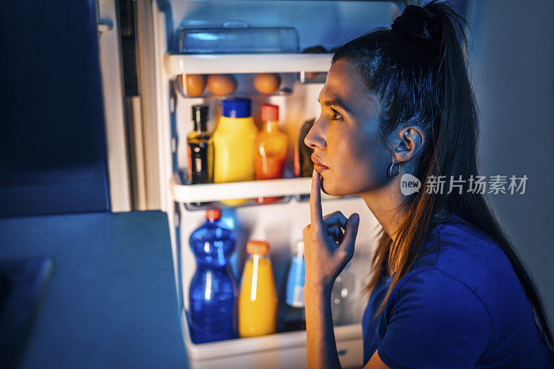 一个女人在冰箱前找吃的