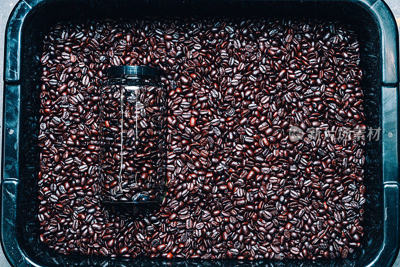 景观工作室拍摄的玻璃梅森罐中等烘烤的咖啡豆放置在一个烘烤的豆子的储存箱背景与复制空间