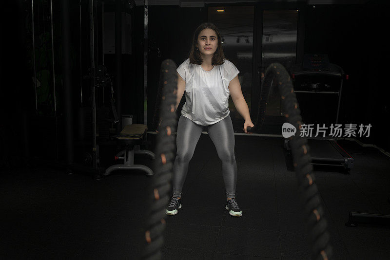 健身女训练战斗绳健身在健身房。
