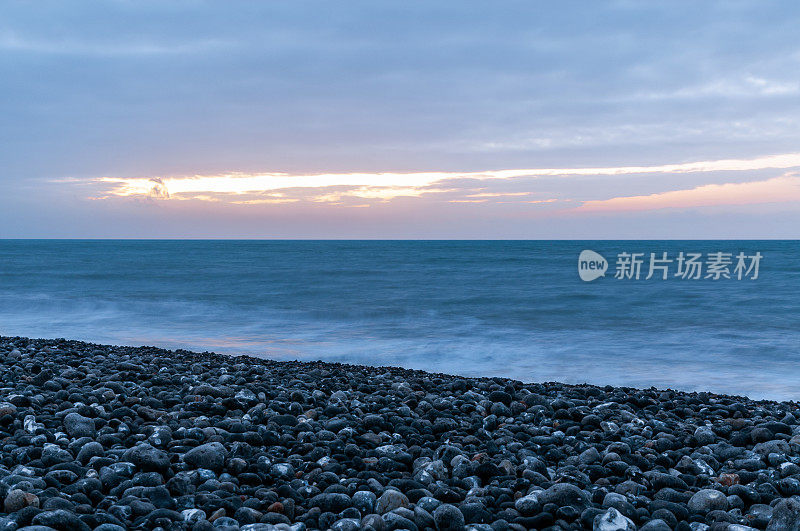 日落在海上，在法国北部的卵石海滩