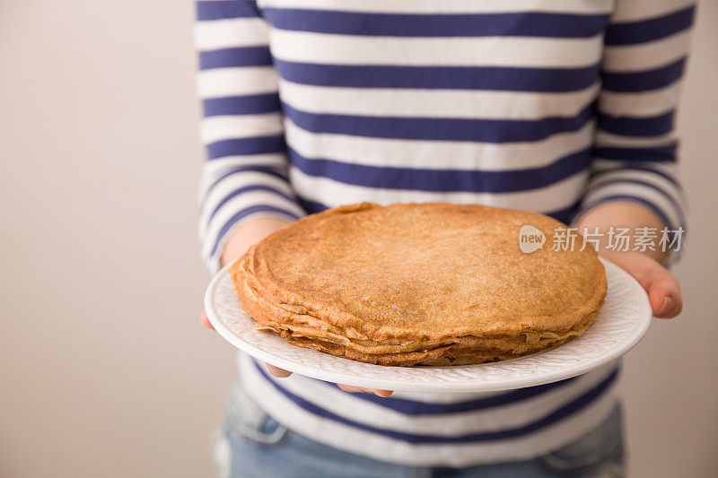 一个女人的手拿着一盘自制煎饼的特写。健康饮食。