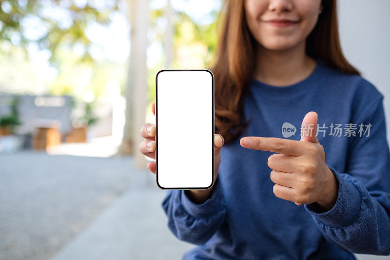 模拟图像的一个年轻的亚洲妇女持有和指着一个空白屏幕的手机手指