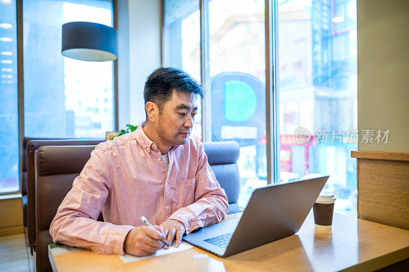 亚洲中年男子在咖啡店使用笔记本电脑