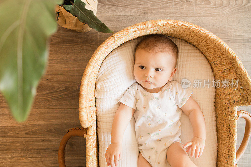 一个29周大的男婴在一个舒适的棉毯在海草摩西篮子在中性现代的家