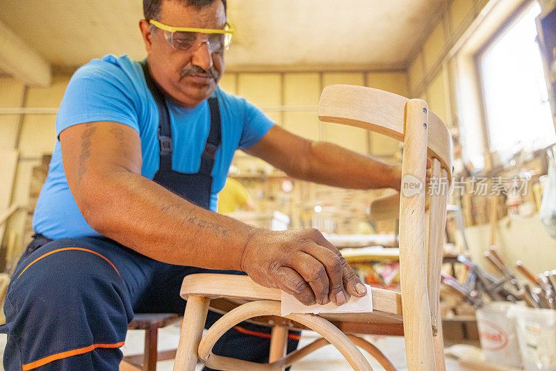 印度木匠独自在他的车间工作。他戴着安全眼镜