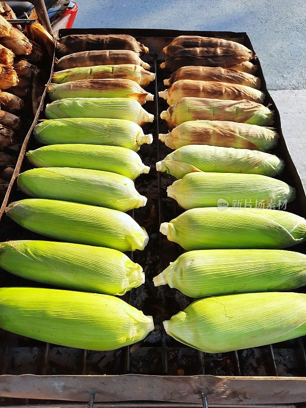 烹饪烤玉米-曼谷街头的食物小贩。