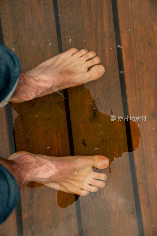 一个人的脚在被洪水淹没的木板路上