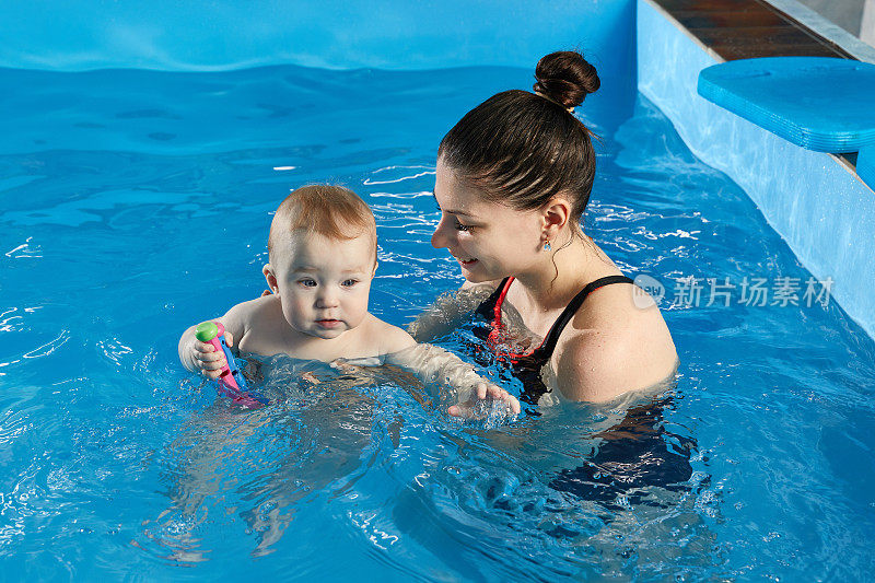 小婴儿和老师一起在泳池里学游泳