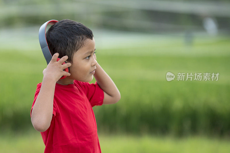 蹒跚学步的男孩用耳机听音乐