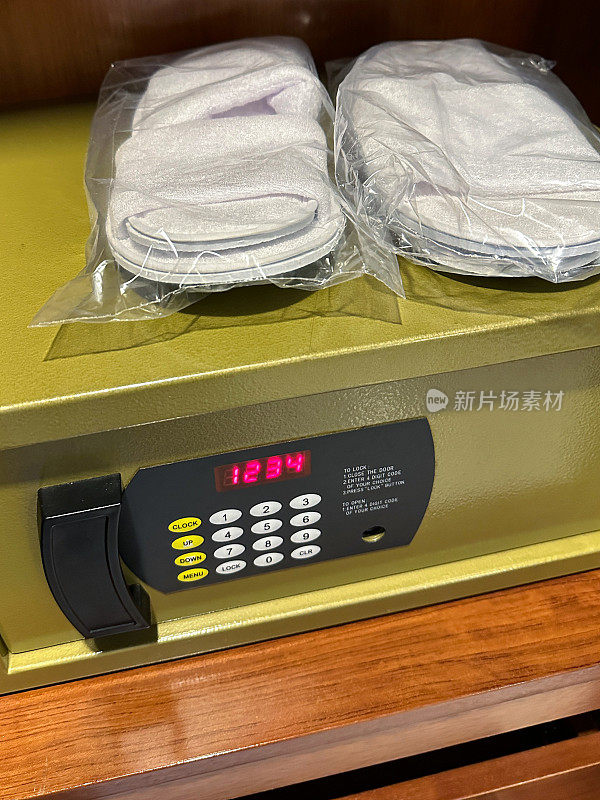 酒店电子酒店衣柜保险箱的特写图像，在键盘上显示1234位数字密码，贵重物品和钱的保险箱，两双毛巾拖鞋，重点在前景