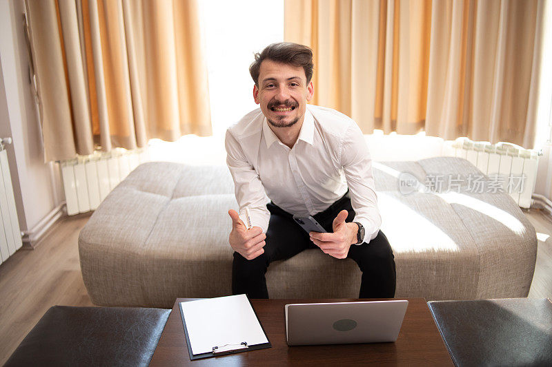 一名年轻的波兰男子穿着白衬衫，在酒店房间里用笔记本电脑上网