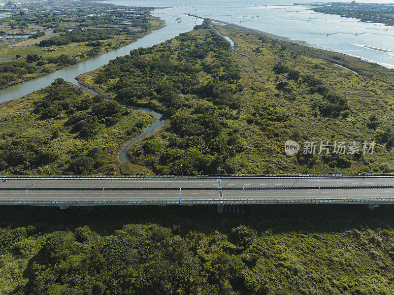 汽车在高速公路路口行驶的鸟瞰图。桥梁道路与绿色花园和树木相连接的建筑概念。