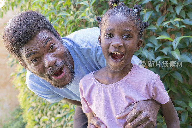 幸福的黑人父亲和小女儿的肖像在户外花园的背景
