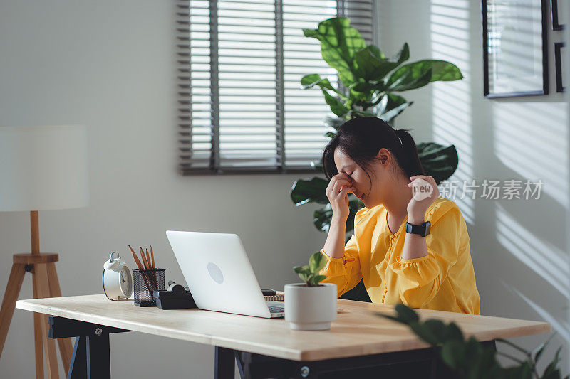 亚洲女性坐在家里办公，眼睛痛。