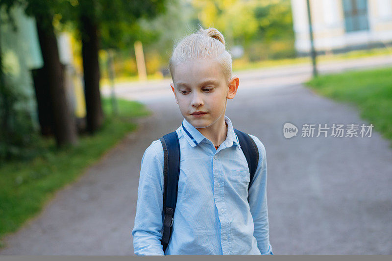 白人男孩背着书包从学校走出来。学年开始了