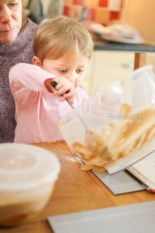 奶奶在厨房的桌子上教她的孙子如何准备蛋糕混合物