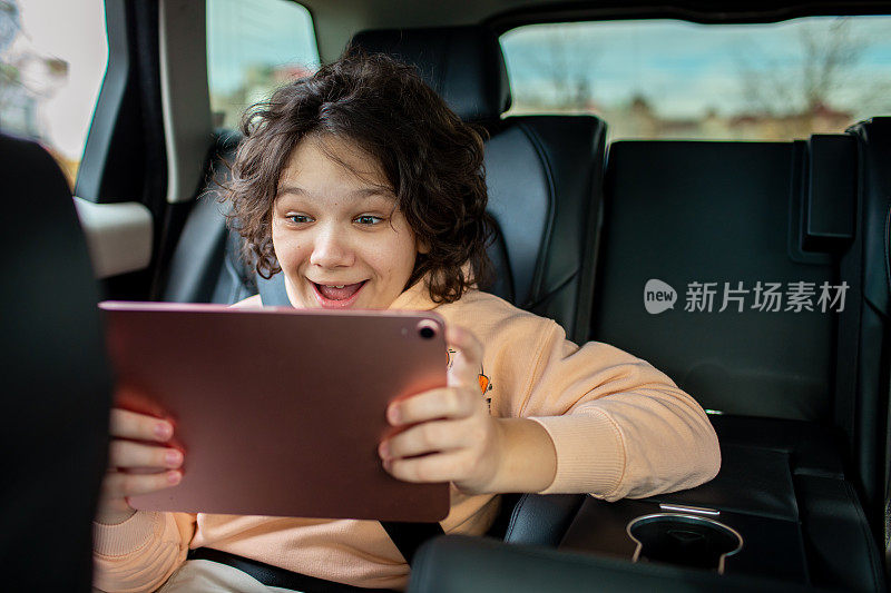 小男孩在汽车后座上玩数码平板电脑