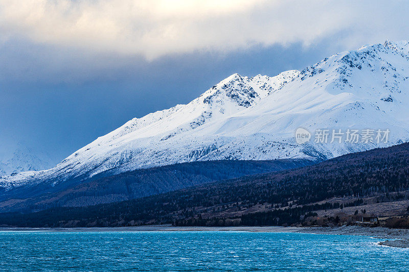 绿松石湖与戏剧性的景观雪山的背景